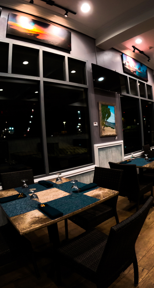 SeaRock dining room in the evening - candlelit tables, warm wood floors and island art