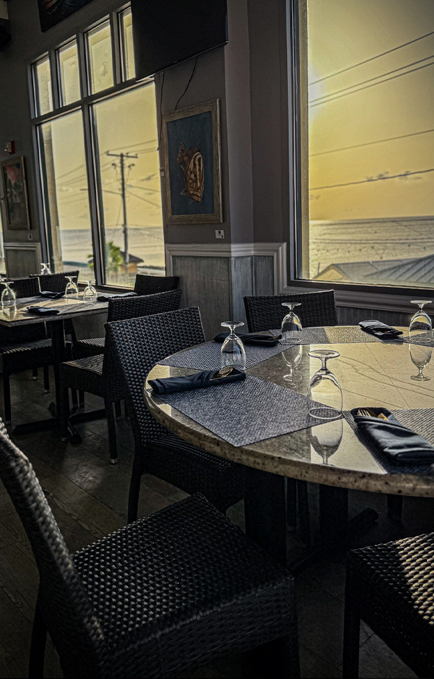 SeaRock's dining room by the windows as the sun sets over George Town harbour