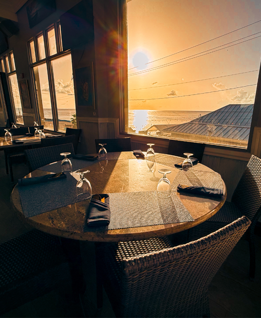 A table set by the harbour window at SeaRock, George Town water glowing at golden hour